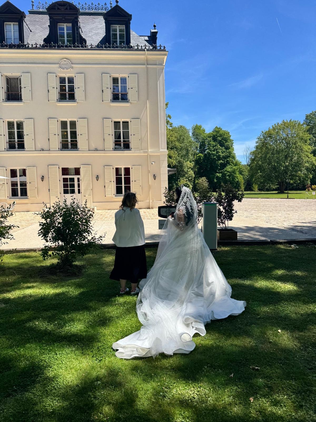 Wedding planner accompagnant une mariée en robe blanche devant un château